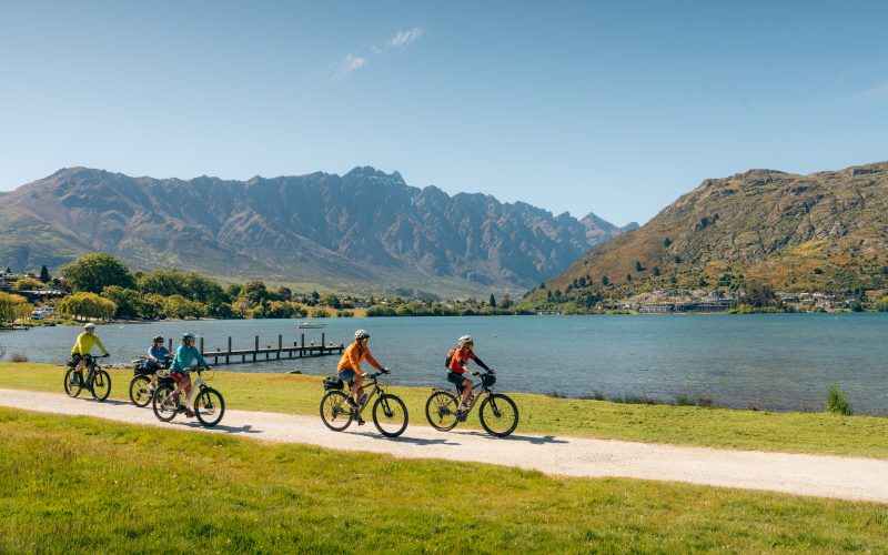 Riders beside Frankton Arm on the Queenstown Trails, The Remarkables behind