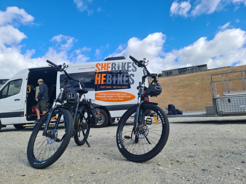 Two Sinch e-bikes set up beside the SheBikesHeBikes van